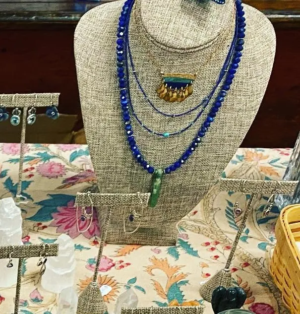 Blue beaded gemstone necklaces on a linen display bust