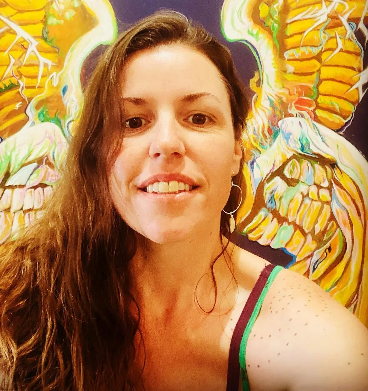 Laura Ellen smiling in front of painted golden wings